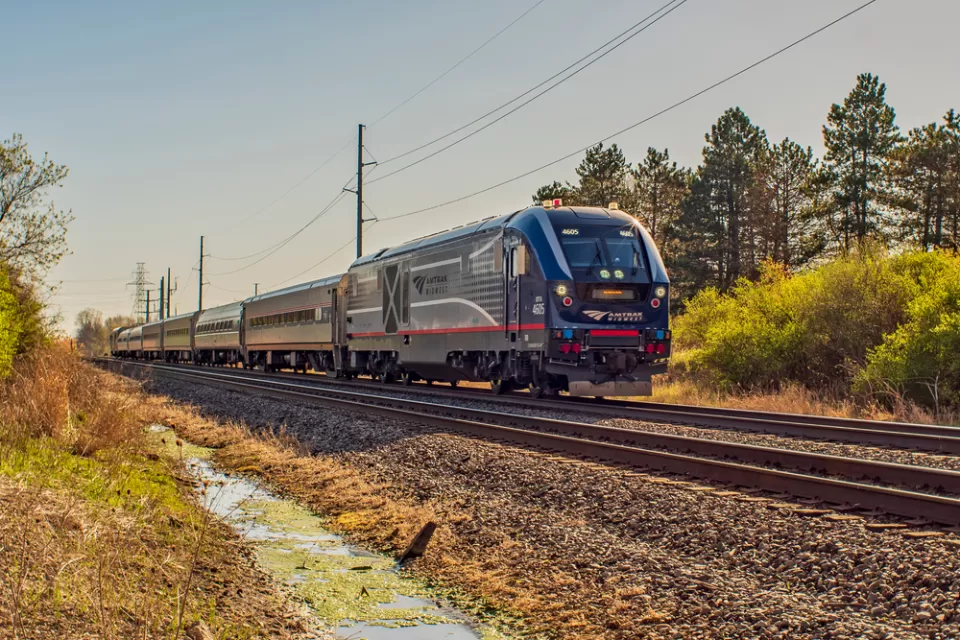 An Amtrak passenger train is shown on a spring day, rolling through a rural area in Missouri.